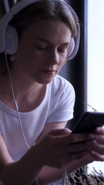 Online sohbet için cep telefonu kullanan memnun bir kadın, evde internet eğlencesinin tadını çıkaran, mutlulukla dijital bağlantı kuran. Dikey video.