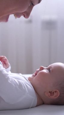 Mutlu anne evde bebekle oynuyor, aile eğlencesini paylaşıyor ve neşeli bir etkileşimle çocukluk anıları yaratıyor. Dikey video.