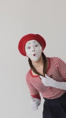 Pandomimci sanatçılar, beyaz bir arka planda, anlamlı ve kutlayıcı hareketlerle onay ve zafer sinyalleri veren bir jest sergiliyorlar. Dikey video.