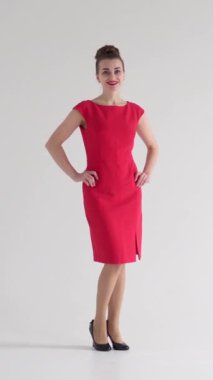 Beyaz arka planda bir portrede pozitif ve oyuncu bir kadın, canlı ve çekici bir ifadeyle zevki, eşsizliği ve kadınlığı sergiliyor. Dikey video.