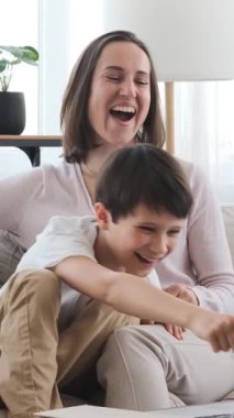 Mutlu anne ve oğul hafta sonu evde film izleyip, keyifli vakit geçiriyorlar. Dikey video.