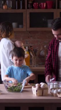 Mutlu bir aile yemeği, evde yemek için sebze doğrama, işbirlikçi ve keyifli bir mutfak deneyimi. Dikey video.