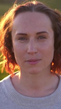 Doğal bir manzarada huzurlu ve tatmin edici bir anın tadını çıkaran, doğa ile çevrili bir arazide yürüyen mutlu ve memnun bir kadının portresi. Dikey video.