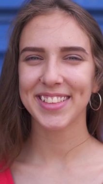 Neşeli ve heyecanlı bir kadının portresi kameraya bakıyor, bireyselliği açık havada keyif alarak sergiliyor. Dikey video.