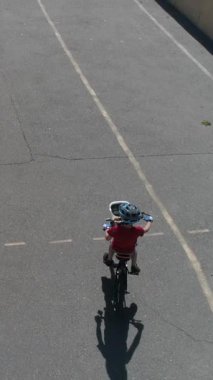 Aktif ve sportif bir çocuğun gündüz açık havada bisiklet sürüşünü, enerjik bir çocukluk ve eğlence anı. Dikey video.