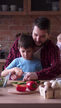 Dost canlısı bir aile, evdeki mutfakta birlikte yemek pişiriyor, sıcak ve keyifli bir ev işiyle işbirliği yapıyor. Dikey video.