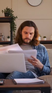 Evde bilgisayarla ve belgelerle e-öğrenim yapan, eğitime disiplinli bir yaklaşımla planlama ve okuma yapan konsantre bir öğrenci. Dikey video.