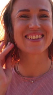 Dost canlısı gülümseyen bir kadının portresi tatil sırasında doğa manzarasında yürümekten zevk alıyor. Açık havada olumlu duygular. Dikey video.