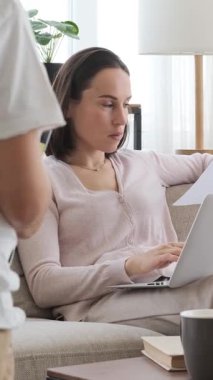 Anne evde çalışırken, öğrenim ve öğrenimi uyumlu ve odaklanmış bir şekilde dengeleyerek ev ödevi yapan oğul öğrenci. Dikey video.