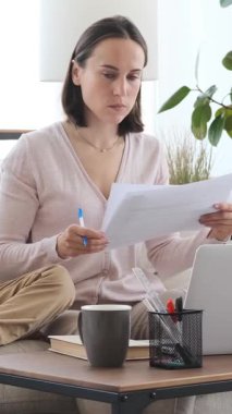 Evlat, evde bilgisayarla çalışan annesinin dikkatini dağıtmak için telefon kullanıyor. Odaklanmış çalışma alanında eğlenceli bir kesinti yaratıyor. Dikey video.