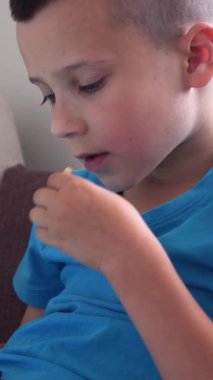 Evde çevrimiçi eğlence için tablet bilgisayar kullanan pozitif çocuk, siber alemden keyif alıyor ve rahat bir ortamda hareketli ve çekici bir tavır sergiliyor. Dikey video.