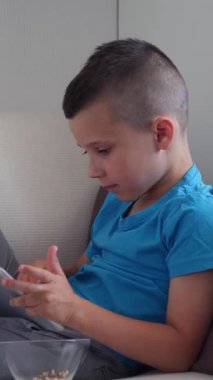 Bilgisayar oyunu oynamak için tablet bilgisayar kullanan ya da evde online eğlencenin tadını çıkaran, neşeli ve dijital boş vakitlerden keyif alan bir çocuk. Dikey video.