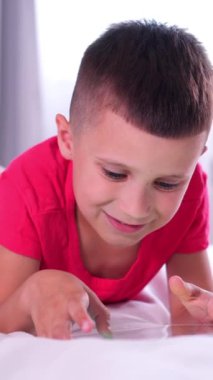 İçerikli çocuk online eğlence ve evde zaman geçirmek için tablet kullanıyor. Ev işleri sırasında teknolojik rahatlama. Dikey video.