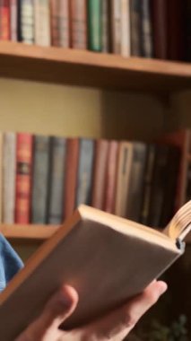 Evde kitap okuyan bir adam, meditasyon ve zevk dolu bir meşgaleyle meşgul, sakin ve rahat bir ortamda dinlenme ve rahatlama buluyor. Dikey video.