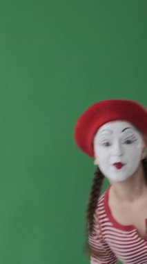 Tatmin olmuş pandomimci kadın yeşil arka planda bir onay sembolüyle benzer bir jest yaparak anlamlı hareketlerle tatmin oluyor. Dikey video.