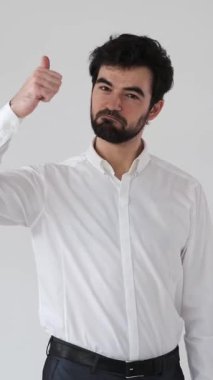 Tatmin olmuş bir adam beyaz bir arkaplanda benzer bir jest sergiler, bu da anlaşmanın, memnuniyetin, seçimin ve tavsiyenin özgüvenli ve olumlu bir tavır içinde olduğunu gösterir. Dikey video.