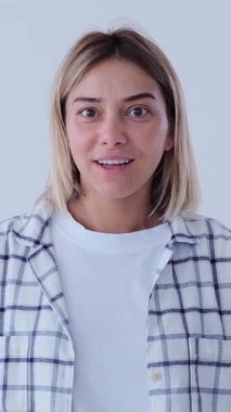 Üzgün kadın, utancını, başarısızlığını ve mağlubiyetini bembeyaz arka planda belirterek, mutsuz duygular gösteren bir yüz ifadesi sergiliyor. Dikey video.