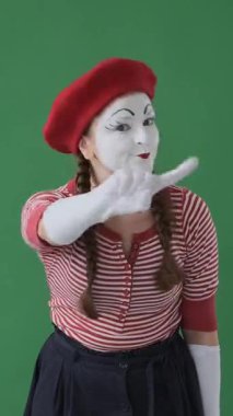 Ciddi pandomimci yeşil arka planda parmak sallayarak veya reddederek otorite ve odaklanmayla sağlam bir mesaj iletiyor. Dikey video.