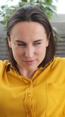 Tatmin olmuş bir kadının portresi müzik eşliğinde dans ediyor ve evde boş zamanlarında eğleniyor, rahat bir ortamda hareketli hareketler yaparak neşeyi ifade ediyor. Dikey video.