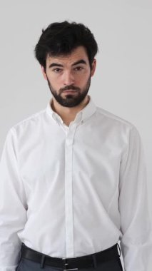 Beyaz arka planda bir portrede kameraya bakan şaşırmış bir adam, çarpıcı ve anlamlı bir tavırla şaşkınlık, şok ve inançsızlığı aktarıyor. Dikey video.