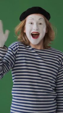 Olumlu pandomimci yeşil arka planda sıcaklığı ve bağlantıyı ifade eden jestler kullanarak hoş geldin diyor. Dikey video.