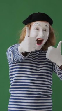 Gülümseyen adam pandomimci yeşil arka planda olumlu bir ifadeyle uzlaşma ve memnuniyeti ifade ediyor. Dikey video.
