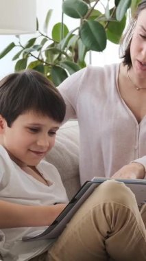 Anne ve oğul ev ödevi yapıyor ve evde birlikte öğreniyor, ortak ve odaklanmış bir yurtiçi alanda eğitimi paylaşıyor. Dikey video.