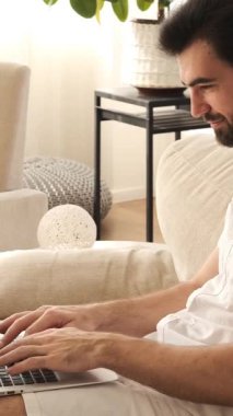 Ciddi bir adam evde dizüstü bilgisayarla çalışıyor, muhasebe, planlama ve teftiş işleriyle uğraşıyor, yapılandırılmış bir ortamda odaklanmış görevlerle uğraşıyor. Dikey video.