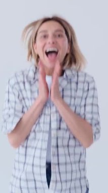 Gülümseyen kadın, beyaz arka planda mutabakat ve destek göstererek olumlu bir ifadeyle onaylar. Dikey video.