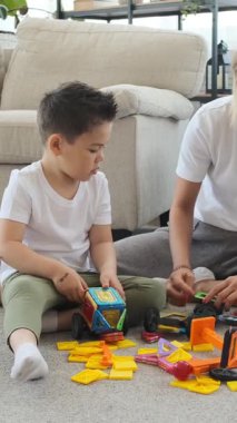 Arkadaş canlısı anne ve okul çocuğu evde bir inşaat setiyle birlikte oynuyorlar, boş zamanlarında yaratıcı bir şekilde işbirliği yapıyorlar, samimi bir ortamda bağlarını güçlendiriyorlar. Dikey video.