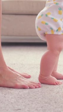 Bir ebeveyn ve bebeğin ilk adımlarını evde birlikte atarak, sıcak ve besleyici bir ortamda bir kilometre taşı boyunca destek ve yardım sağlamaları. Dikey video.