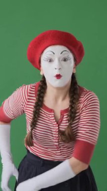 Dost canlısı bir pandomimci kadın yeşil bir arka planda el dürbününden izliyor, keşfin kıvılcımını çıkarmak için merakla gözlem yapıyor. Dikey video.