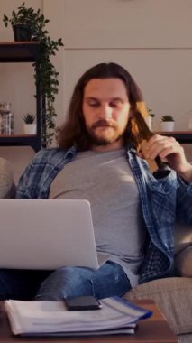 Güler yüzlü adam evde boş zamanlarında bilgisayarla mesajlaşıyor, rahat bir dijital ortamda neşeli bir tavırla iletişim kuruyor. Dikey video.