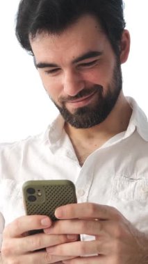 Evdeki telefonu kullanarak internetten mesaj atan heyecanlı bir adam, internet eğlencesine dalmış, rahat ve tanıdık bir ortamda dijital olarak şevkle bağlantı kuruyor. Dikey video.