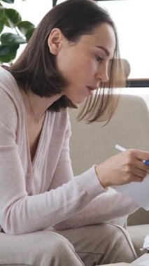 Evladının, evdeki belgelerle çevrimiçi çalışan annesinin dikkatini dağıtması, ev ortamında yoğun işini yarıda kesmesi. Dikey video.