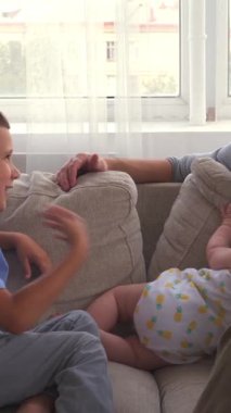 Okul çocuğu ve babası evdeki bir kanepede, sıcak ve sıcak bir atmosferde iletişim kurarak aile eğlencesi sırasında sohbet ederler. Dikey video.