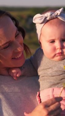Anne ve bebek gün batımında doğa ile çevrili, boş zamanlarında dünyayı keşfediyor, huzurlu ve huzurlu bir an yaşıyor. Dikey video.