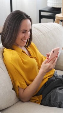 Arkadaş canlısı bir kadın, arkadaşlarıyla çevrimiçi sohbet etmek için sosyal medya aracılığıyla evdeki bir video görüşmesi sırasında kolaylıkla iletişim kuruyor. Dikey video.