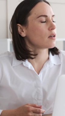 İyimser iş kadını bir internet video görüşmesini yönetiyor ya da ofiste dizüstü bilgisayarla buluşuyor, kendine güvenen belgelerle çalışıyor. Dikey video.