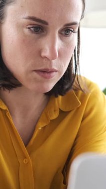 Evinde doküman ve dizüstü bilgisayarla çalışan, strateji geliştiren ve muhasebeyi titizlikle yöneten bir kadının yakın çekimi. Dikey video.