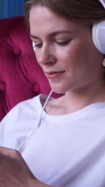 İnternette gezinmek için telefon kullanan olumlu bir kadın ve evde online hobi, sakin bir dijital ortamda rahatlama buluyor. Dikey video.