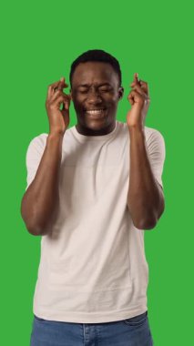 Heyecanlı Afrikalı Amerikalı yetişkin bir adam yeşil arka planda şans diliyor..