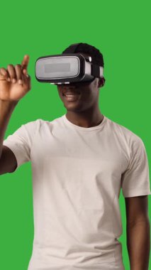 VR kulaklık takan ve yeşil fonda el kol sallayan bir adam..