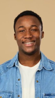 Kollarını bej arka planda kavuşturan mutlu yetişkin bir adam..