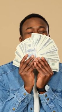 Mutlu yetişkin adam bej arka planda elinde bir sürü para tutuyor..