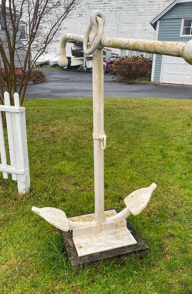 An old white medal anchor on the fron lawn of a historic boatyard in Babylon Village, Long Island.