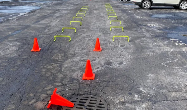 Small yello hurdles set u in tow rows in a parking lot for a high school track team to run over after a snow storm covered the track.