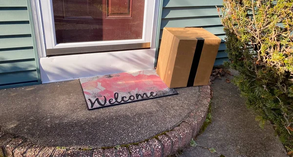 A package is delivered and placed on the front stoop of a residential home leaving it vulnerable to be stolen.