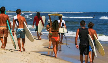 Bir grup sörfçünün Gilgo Sahili 'nin kıyısındaki sörf tahtalarını taşıdığı arka manzara..
