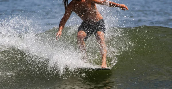 男はサーフボードの前に立ってサーフィンしている間 水が飛び散る — ストック写真